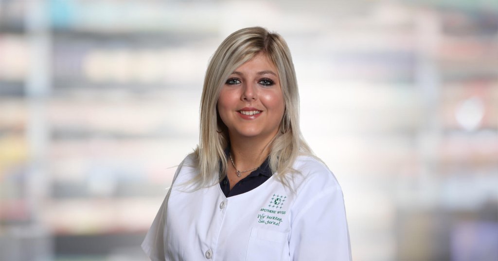 Deborah Sutter, eine Frau mit langen blonden Haaren und einem wei&szlig;en Arztkittel, l&auml;chelt in die Kamera. Der Hintergrund ist sanft mit hellen Farben verschwommen.