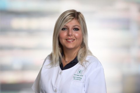 Deborah Sutter, eine Frau mit langen blonden Haaren und einem wei&szlig;en Arztkittel, l&auml;chelt in die Kamera. Der Hintergrund ist sanft mit hellen Farben verschwommen.