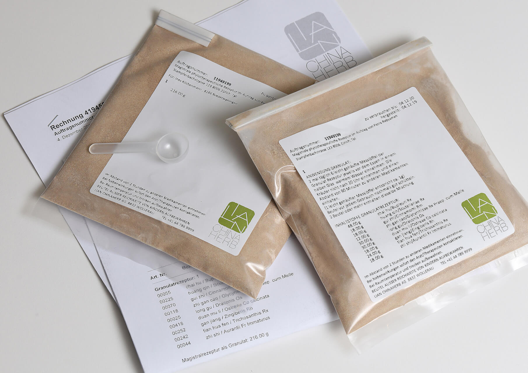 Zwei durchsichtige, mit braunem Pulver gef&uuml;llte Plastikbeutel, die jeweils mit Text und dem LA CHINA HERB-Logo beschriftet sind, stehen auf einer bedruckten Rechnung. Auf einem Beutel liegt eine kleine Schaufel, die die Bequemlichkeit des angebotenen TCM-Abholservices unterstreicht.