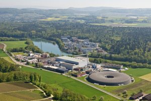 Luftaufnahme einer gro&szlig;en wissenschaftlichen Forschungseinrichtung, in der Medikamente gegen COVID-19 entwickelt werden, mit kreisf&ouml;rmigen und rechteckigen Geb&auml;uden, umgeben von gr&uuml;nen Feldern, W&auml;ldern, einem Fluss und fernen H&uuml;geln unter einem klaren Himmel.