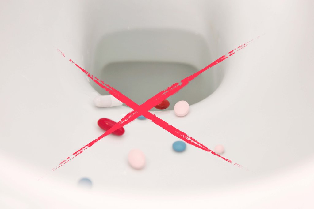 In einer Toilettensch&uuml;ssel sind verschiedene Pillen verstreut, &uuml;ber die ein gro&szlig;es rotes X gezeichnet ist, das auf die falsche Methode der Medikamenten-Entsorgung hinweist.