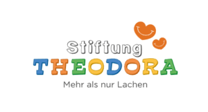 Logo der Stiftung Theodora mit bunten, verspielten Buchstaben und zwei orangefarbenen, l&auml;chelnden Herzformen dar&uuml;ber. Darunter steht Mehr als nur Lachen auf Deutsch - und erinnert uns daran, wie Lachen das Immunsystem st&auml;rken kann.