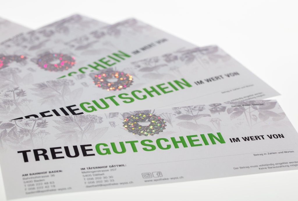 Drei Geschenkgutscheine mit der Aufschrift TREUEGUTSCHEIN, mit gr&uuml;nem und schwarzem Text und silbernen holografischen Siegeln. Auf dem Hintergrund sind schwache botanische Illustrationen, der Wert, die Einl&ouml;seorte und ein dezentes Motiv der Wyss Treuekarte zu sehen.