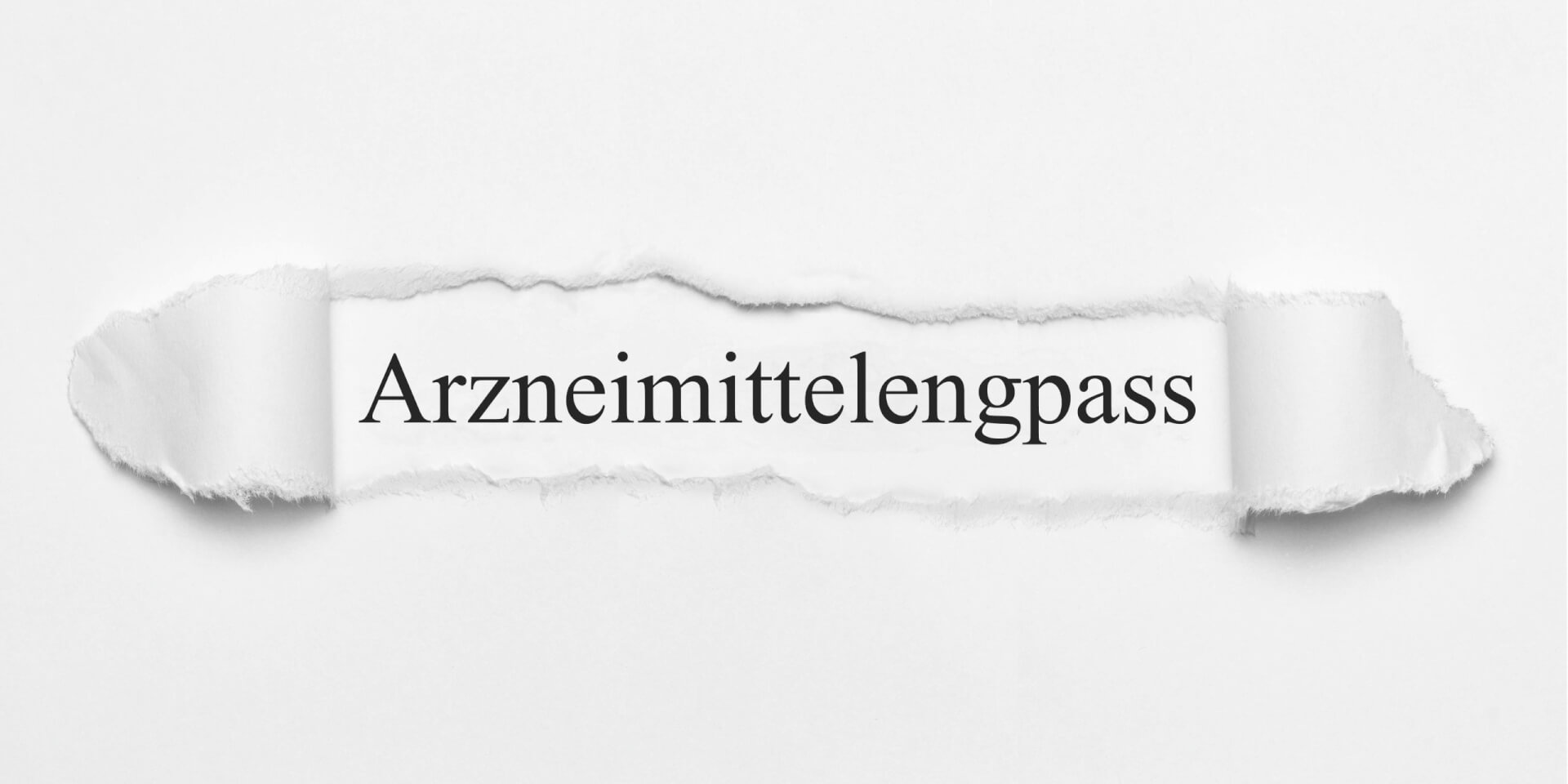 Das Wort Arzneimittelengpass steht zentriert auf weissem Grund, der durch einen horizontalen Riss im Papier sichtbar wird - ein Hinweis auf die Ausgabe des Medikamentenengpasses in der Schweiz.
