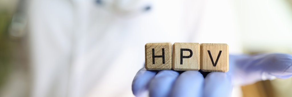 Eine Person mit wei&szlig;em Kittel und blauen Handschuhen h&auml;lt drei Holzkl&ouml;tze mit den Buchstaben H, P und V in der Hand, die HPV und Therapien symbolisieren, um sie zu entfernen.