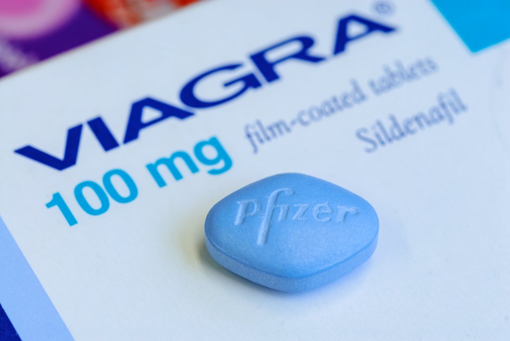 Eine blaue Viagra-Pille mit der Aufschrift Pfizer liegt auf einer Schachtel mit der Aufschrift VIAGRA 100 mg Filmtabletten Sildenafil und weist auf die Gefahr von gef&auml;lschten Medikamenten im Umlauf hin.