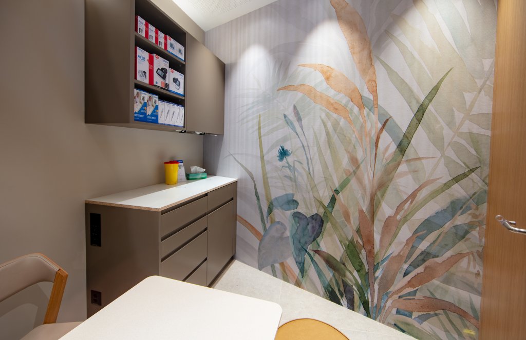 Ein modern gestalteter medizinischer Beratungsraum mit einem Tresen, Schr&auml;nken mit medizinischem Material, einem Stuhl und einem farbenfrohen botanischen Wandbild - wie in der Apotheke Wyss beim Bahnhof Baden.