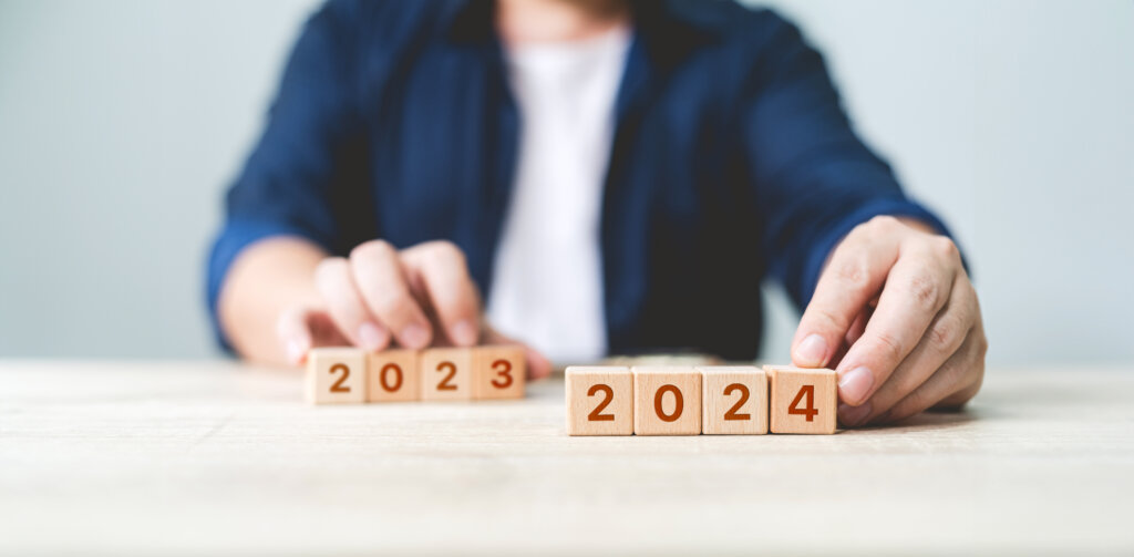 Eine Person wechselt die Holzkl&ouml;tze auf einem Tisch von 2023 auf 2024, was den &Uuml;bergang zum neuen Jahr symbolisiert, &auml;hnlich wie der Beginn einer Fachapotheker-Ausbildung oder einer Apotheker-Weiterbildung f&uuml;r ein neues berufliches Kapitel.