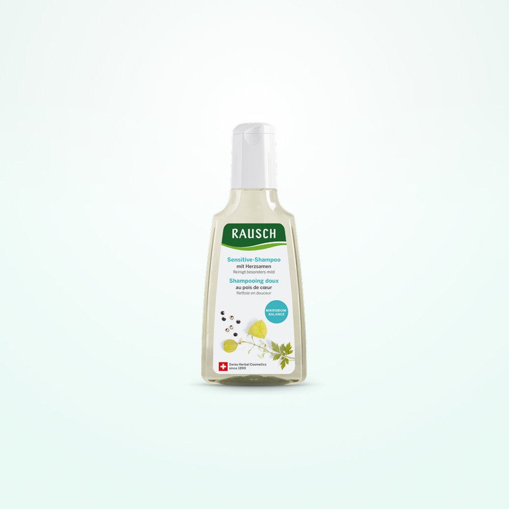 Eine Flasche Rausch Sensitiv Shampoo mit Herzsamen-Extrakt steht aufrecht vor einem hellen Hintergrund. Auf dem grünen Etikett, das in seiner Klarheit der Verpackung von elmex gelée ähnelt, sind auf der Vorderseite Herzsamen und Pflanzenblätter abgebildet.