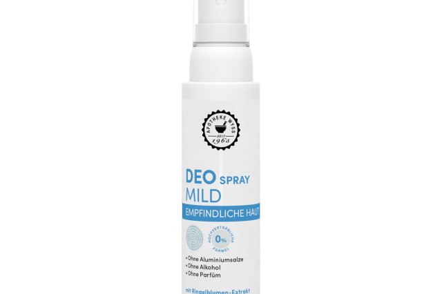 Eine wei&szlig;e Flasche &bdquo;DEO SPRAY MILD&ldquo; f&uuml;r empfindliche Haut mit Spr&uuml;hkopf, blauer und grauer Beschriftung sowie Symbolen und einem schlichten Design. Auf dem Etikett wird darauf hingewiesen, dass das Produkt frei von Aluminium, Alkohol und Duftstoffen ist.